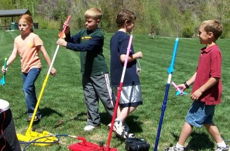 Children launching colorful paper rockets outdoors