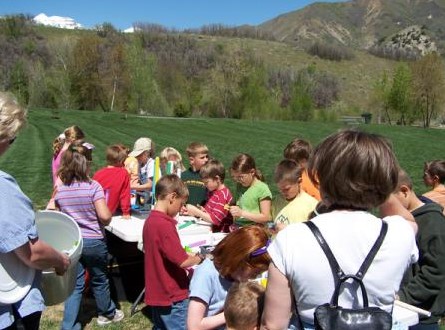 School-age children building rockets at outdoor tables with staff support